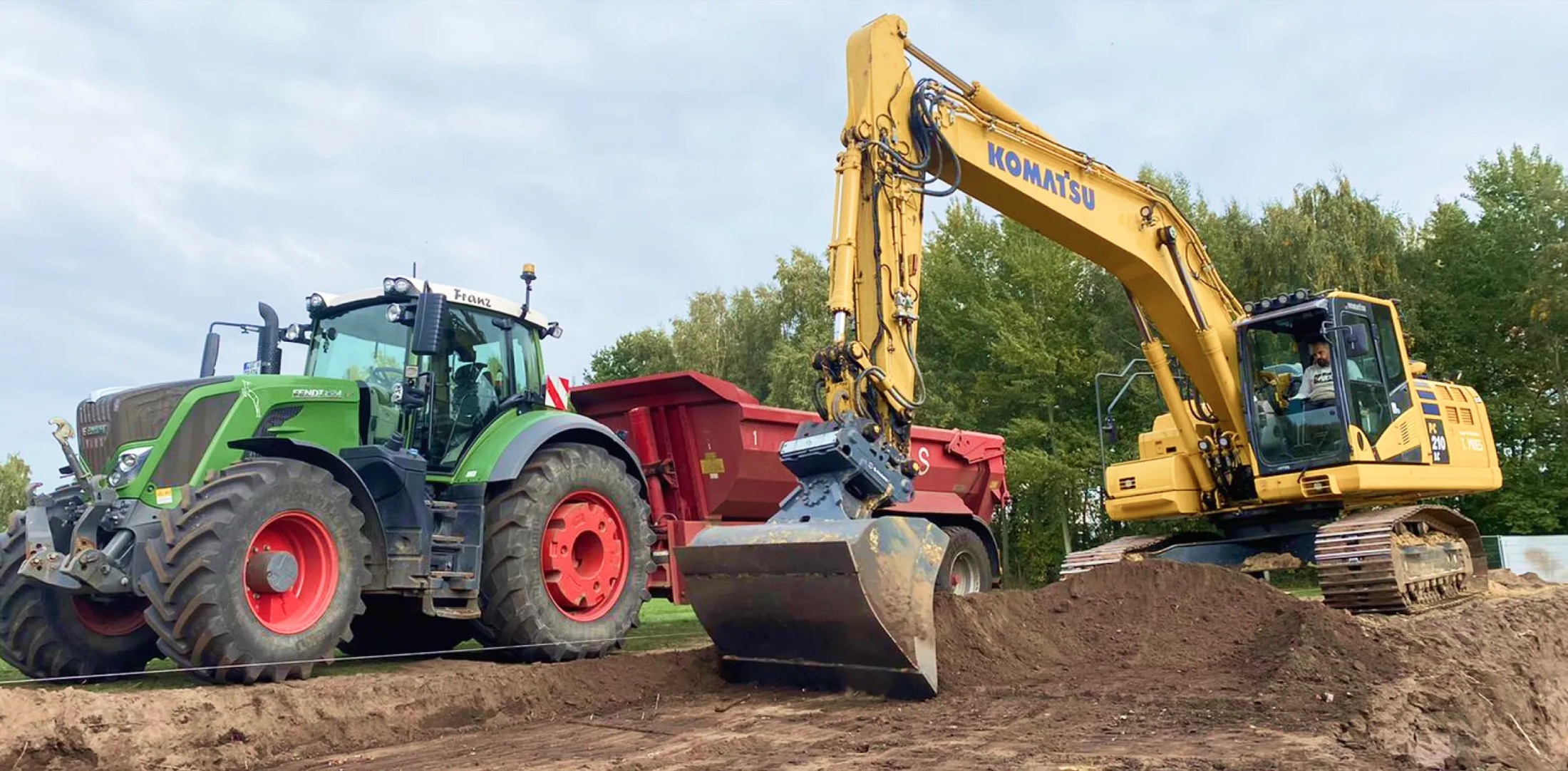 Kettenbagger und Traktor mit Kipper bei Erdarbeiten